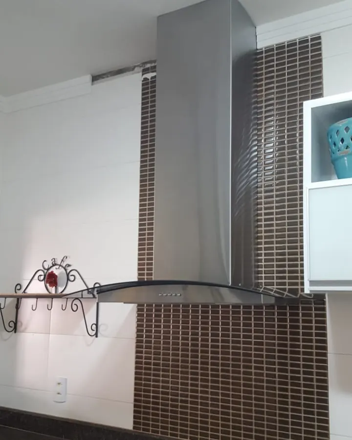 Coifa residencial de vidro curvo instalada sobre fogão