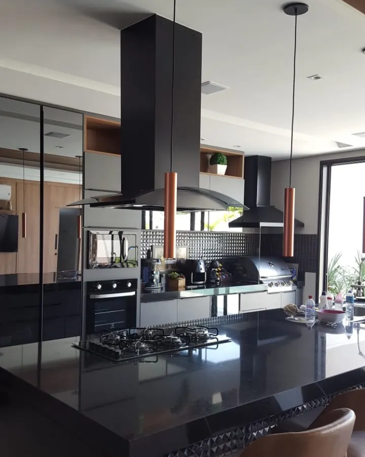 Coifa de ilha preta instalada pela Coifas MM sobre bancada com cooktop